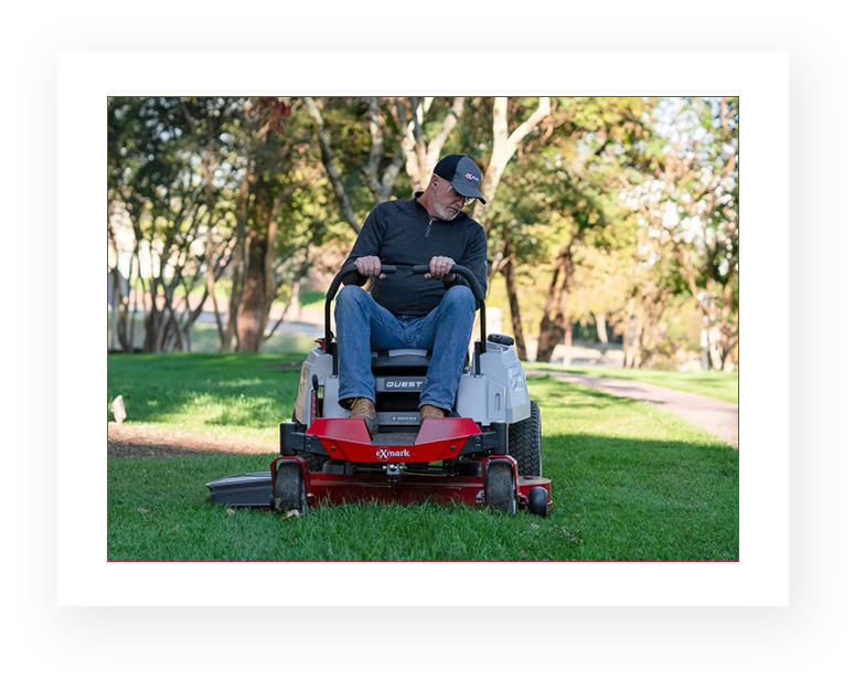 A man sitting on top of a lawn mower.