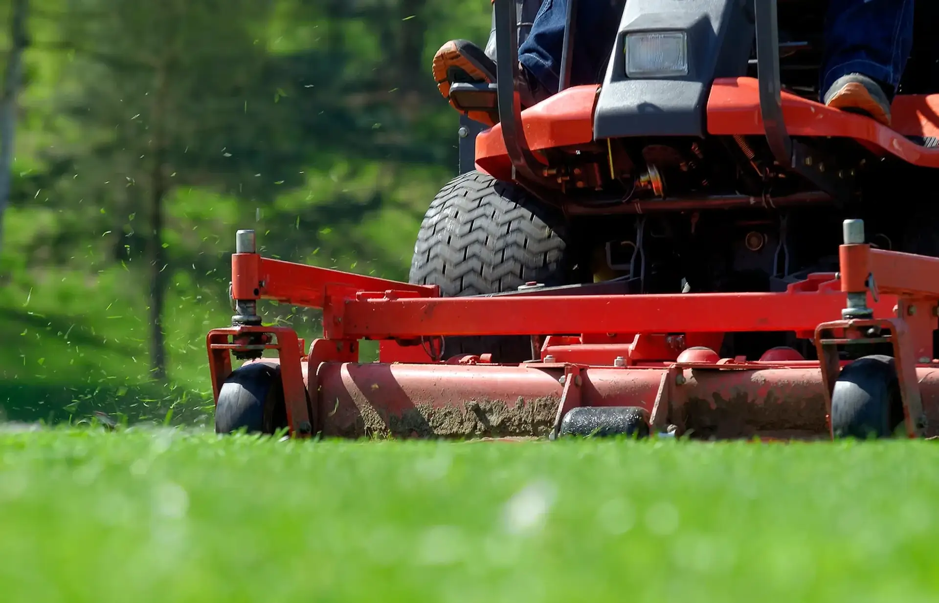 A person on a lawn mower in the grass.